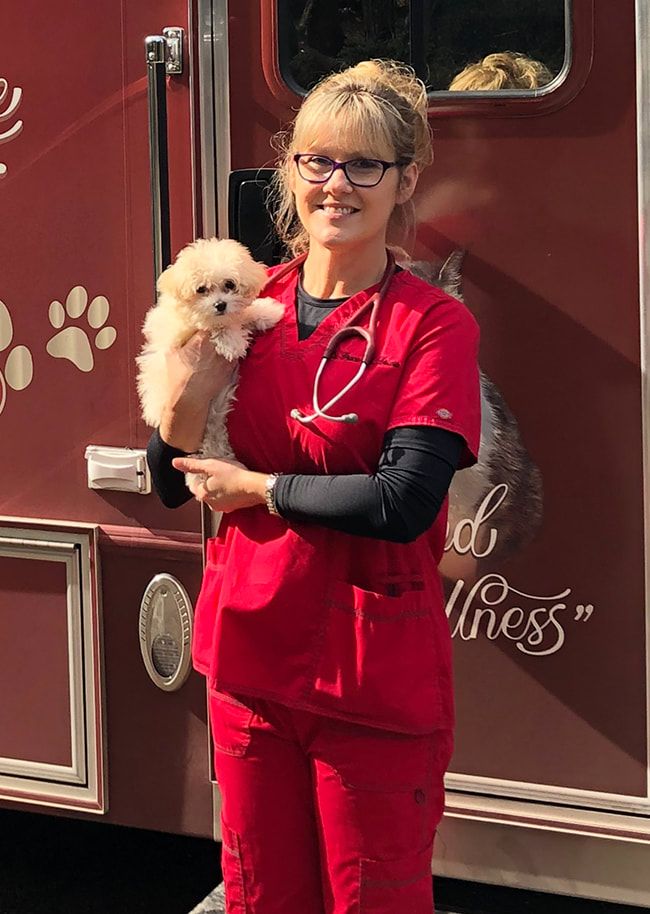 Dr. Grace holding a puppy beside the mobile clinic